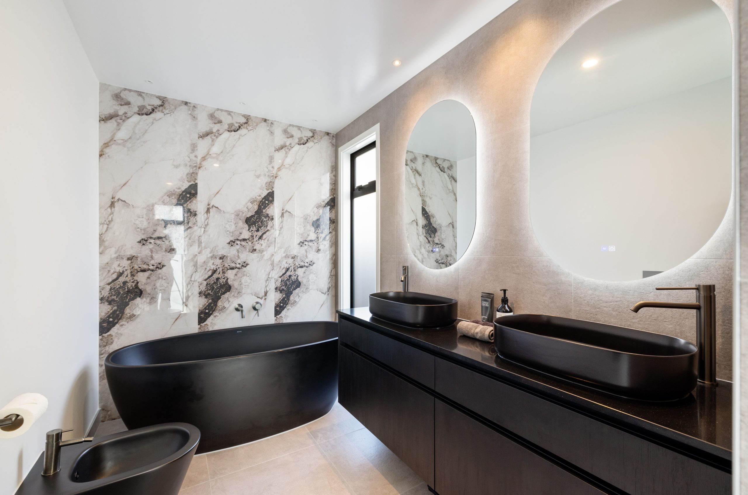 Elegant ensuite with tiled shower, wall-hung vanity, and backlit mirrors