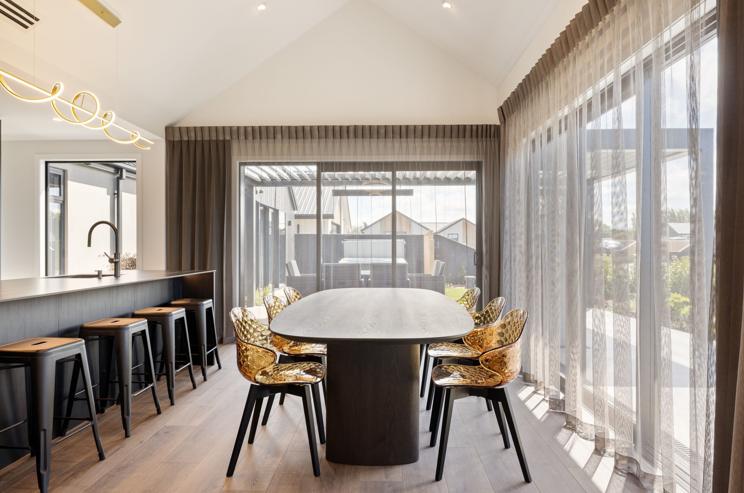 Designer kitchen with waterfall island, sleek cabinetry, and gold accents and designer dining furniture