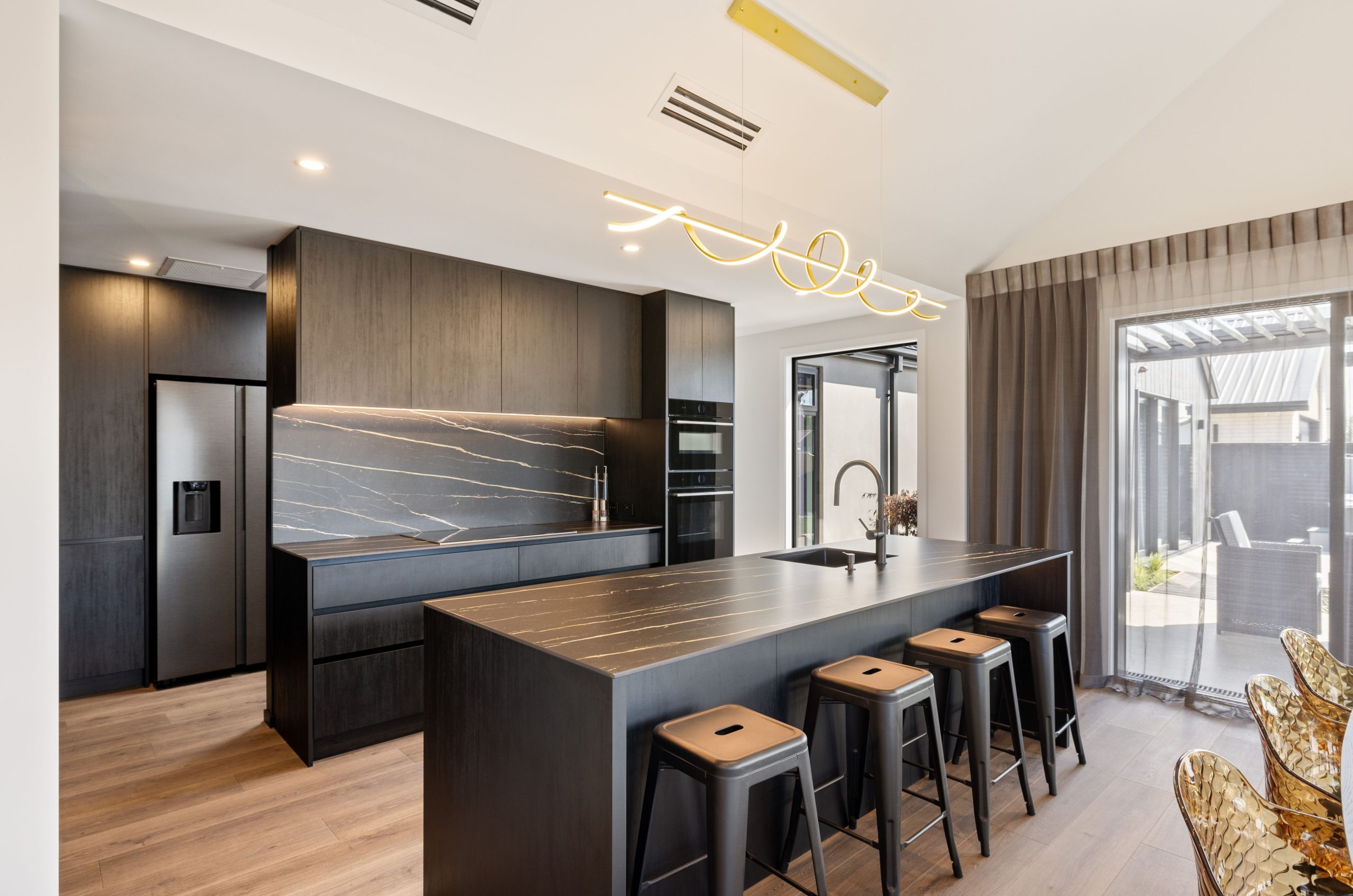 Designer kitchen with waterfall island, sleek cabinetry, and gold accents