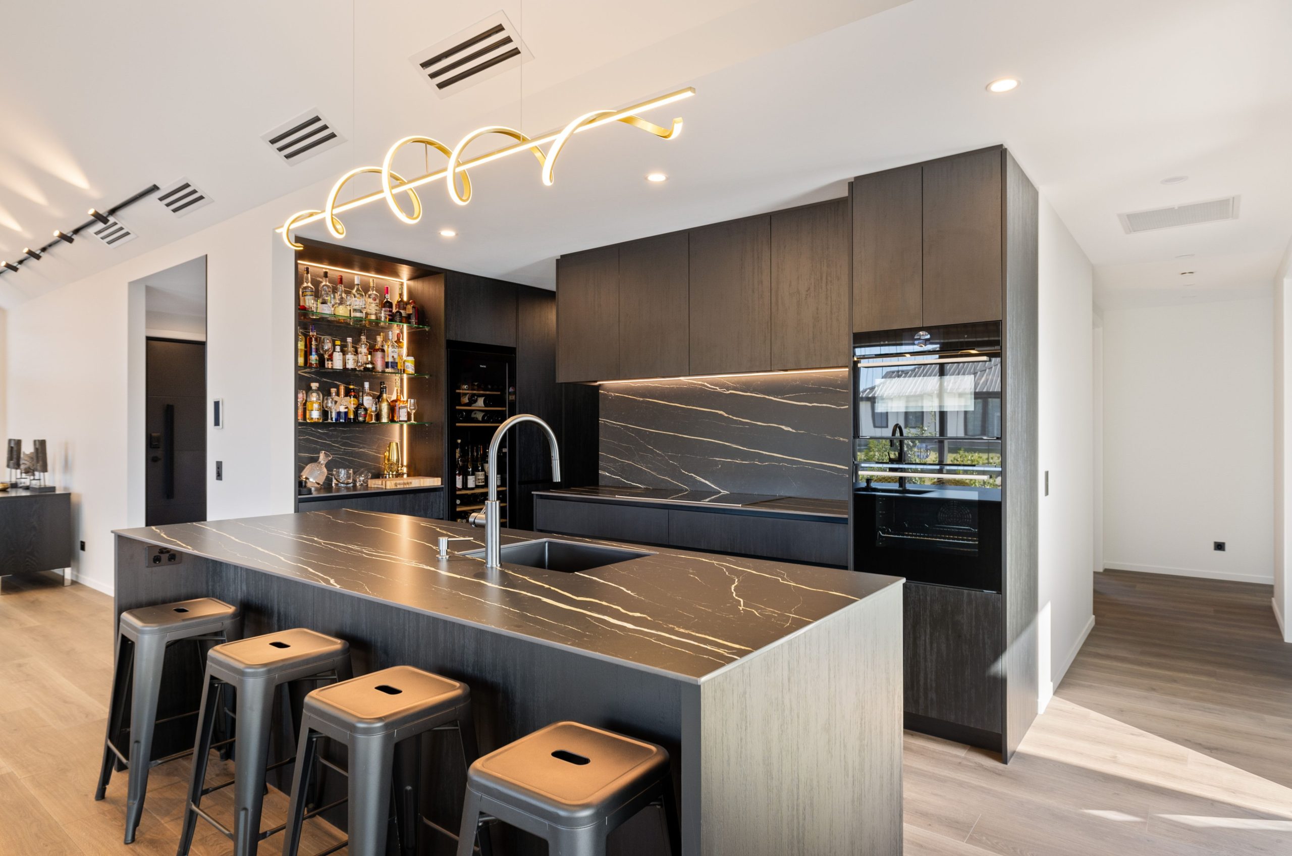 Designer kitchen with waterfall island, sleek cabinetry, and gold accents